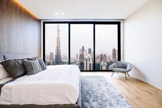 Dubai apartment, bed, chair, panoramic view, Burj Khalifa in background.