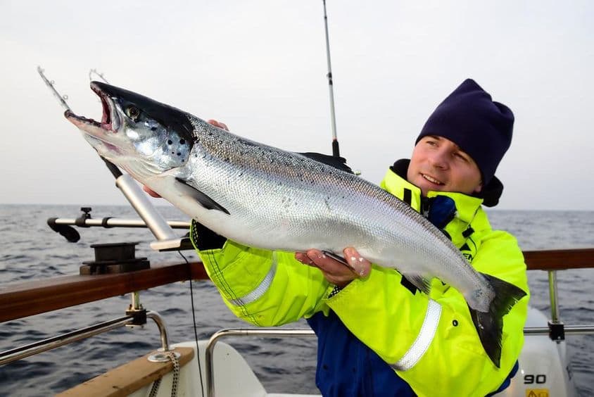 Sea fishing, a fisherman proudly displaying a large catch on a boat.