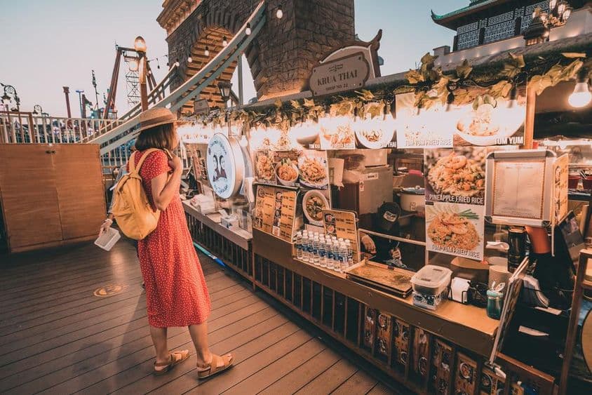 Woman in a red polka dot dress looking at national cuisines at Dubai Global Village.