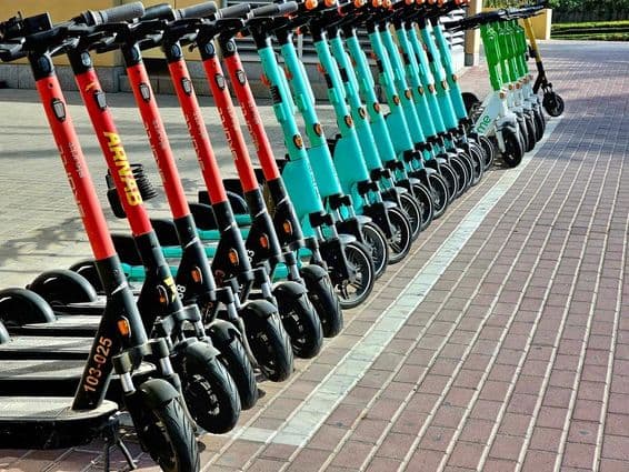 Red, blue, and green scooters waiting in their parking areas.