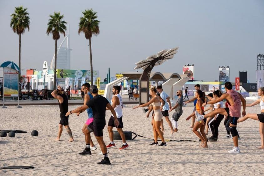 A group of people exercising on a sandy beach during the Dubai Fitness Challenge.