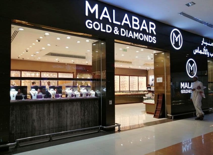 An Emirati stands in front of Malabar Gold & Diamonds store display.