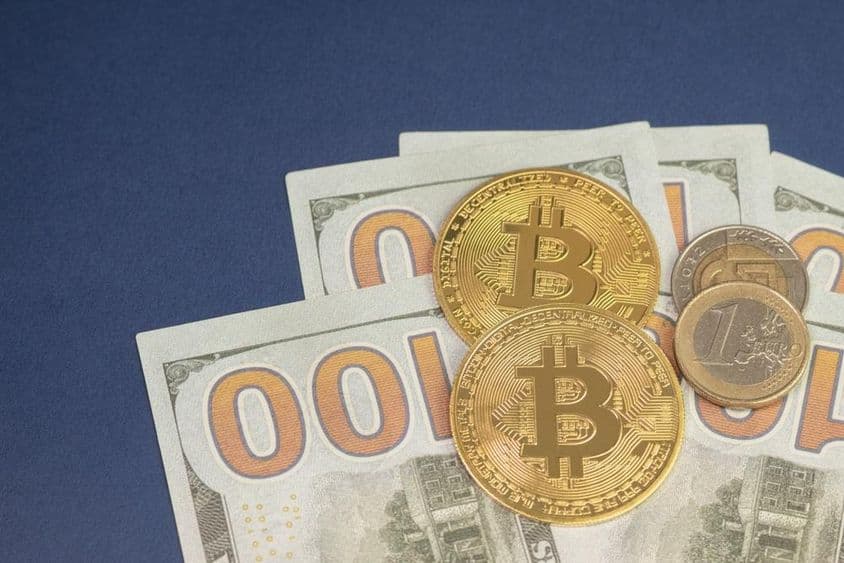 US dollar above bitcoin coins next to 1 euro coin