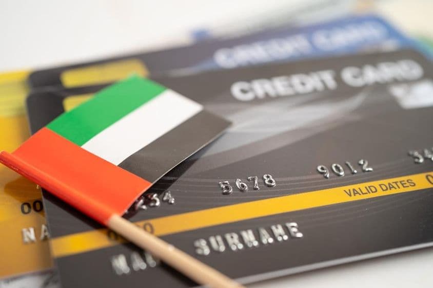 Credit cards lying on a table with a UAE flag paper above them.