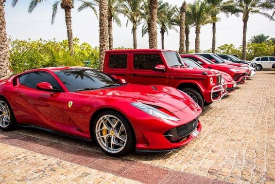Red luxury cars lined up in Dubai, featuring Ferrari, Porsche, Mercedes.