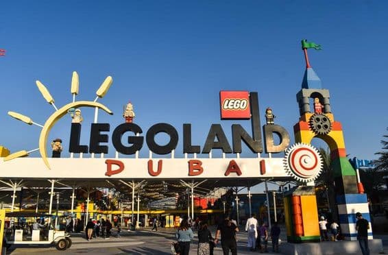 Entrance to LEGOLAND Dubai with people and a golf cart in front.