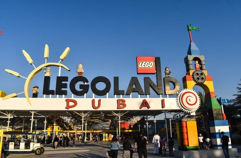 Entrance to LEGOLAND Dubai with people and a golf cart in front.