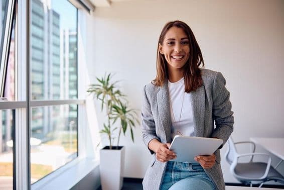White woman in office holding a tablet.