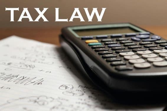 A calculator is on top of a notebook with the label tax legislation above it.