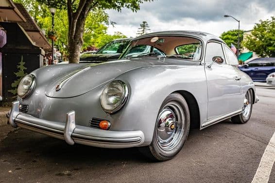 A Porsche 356A is seen parked under a tree.