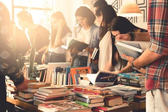 Students browsing through books at a large fair.