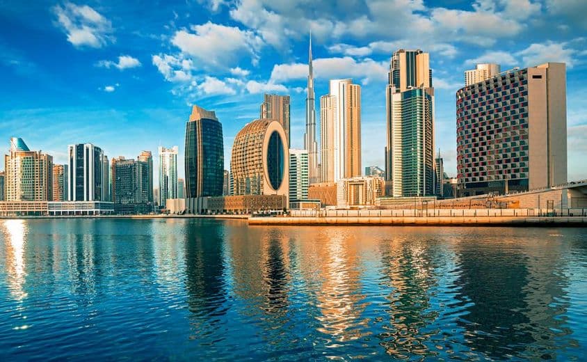 Dubai skyscrapers with water in foreground, Burj Khalifa in background.