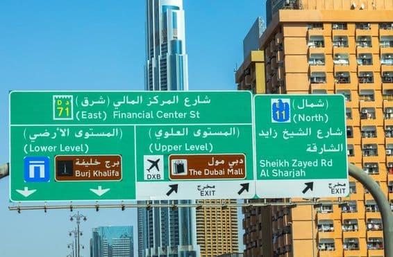 Dubai skyscrapers in the background, road sign in foreground.