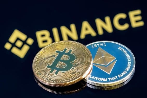 Binance inscription in the background on a black table featuring a Bitcoin and an Ethereum coin.