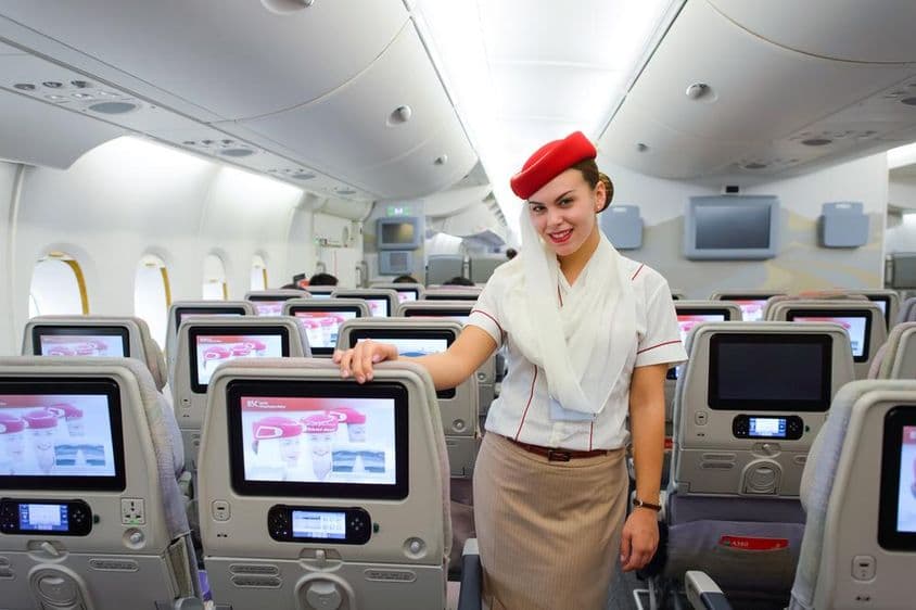 Interior of an Emirates airplane with a flight attendant in the foreground.