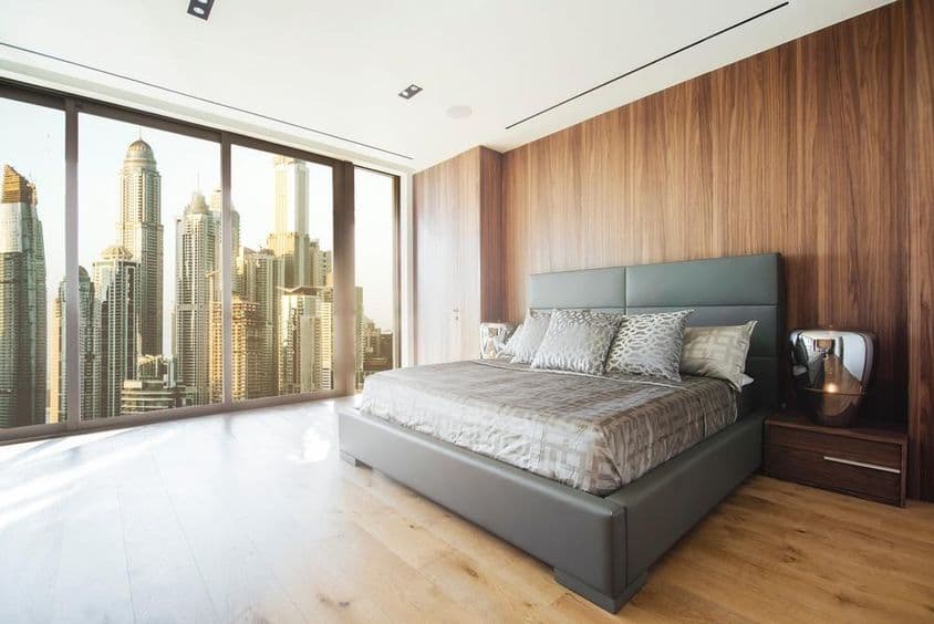 Interior of a Dubai room with bed, window view of skyscrapers.