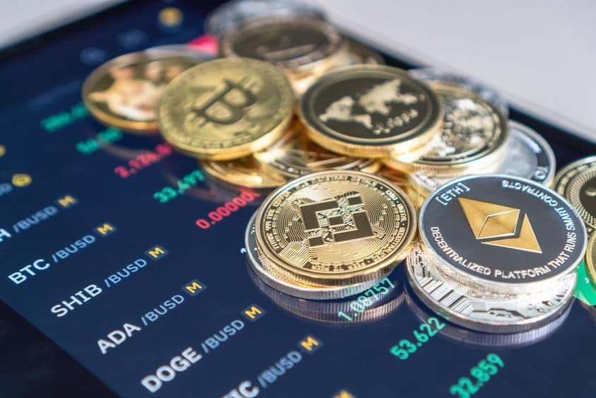 Ethereum and bitcoin coins placed on a phone screen displaying crypto exchange rates.