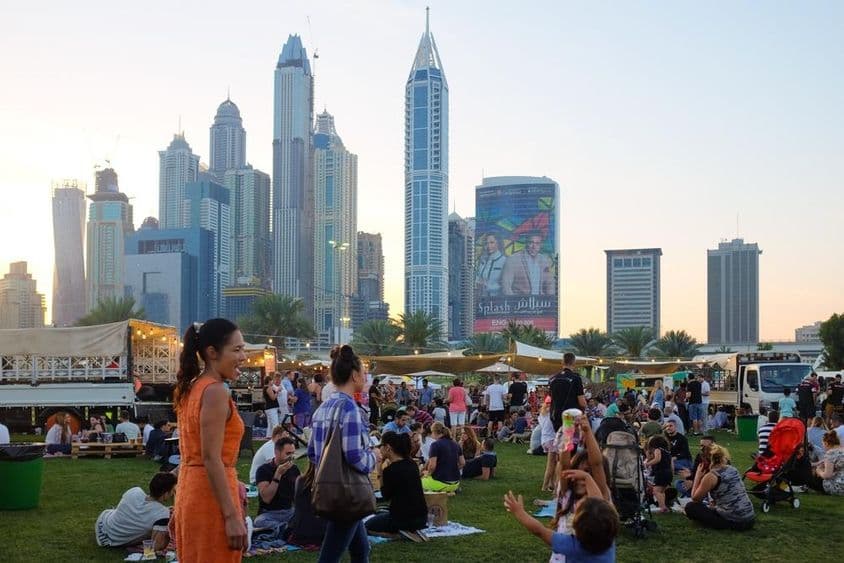 Dubai people sitting in a park, skyscrapers in the background.