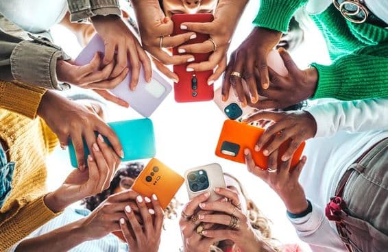 People holding phones in a circle, hands seen from below.