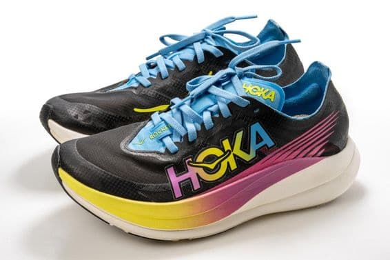 A Hoka sports shoe with colorful pattern, predominantly black, with a white sole.
