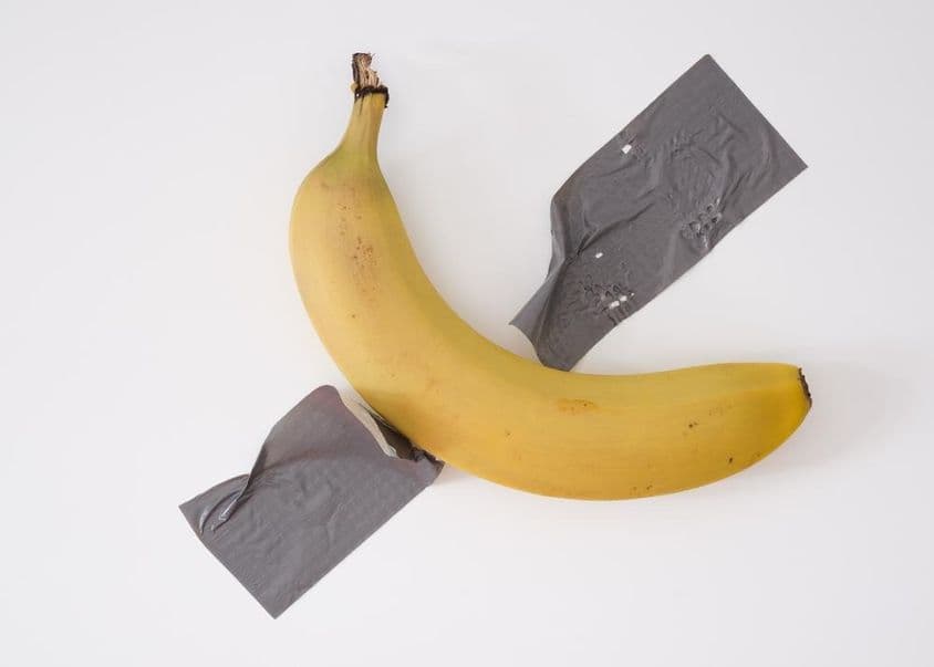 A banana taped to the wall with gray duct tape.