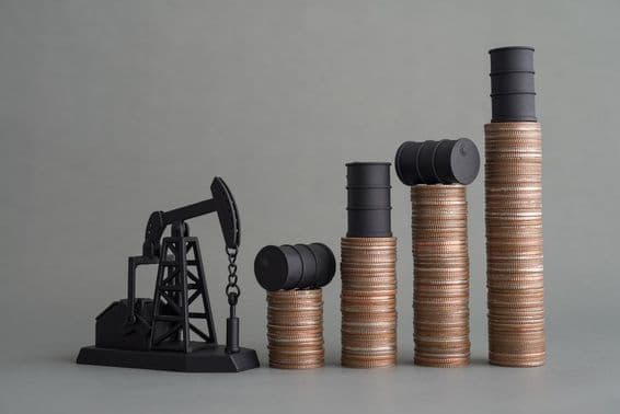Mini oil rig and stacked coins topped with an oil barrel.