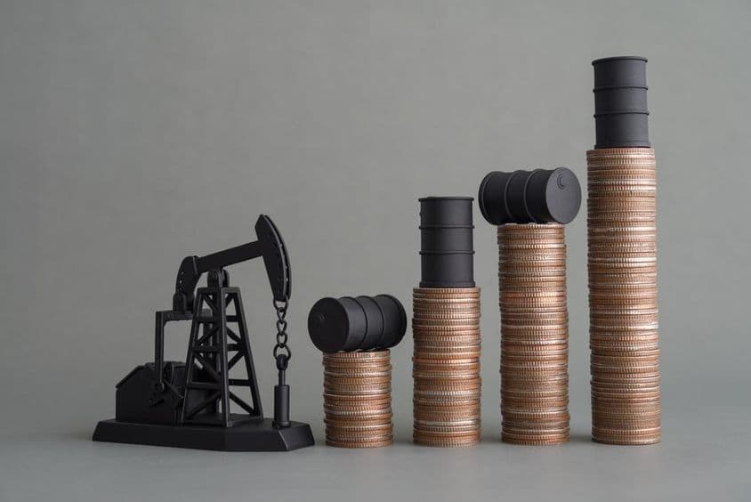 Mini oil rig and stacked coins topped with an oil barrel.