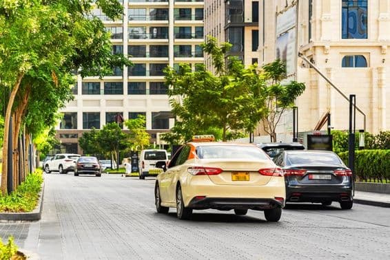 Dubai cars on the road, a taxi in the foreground, houses behind.