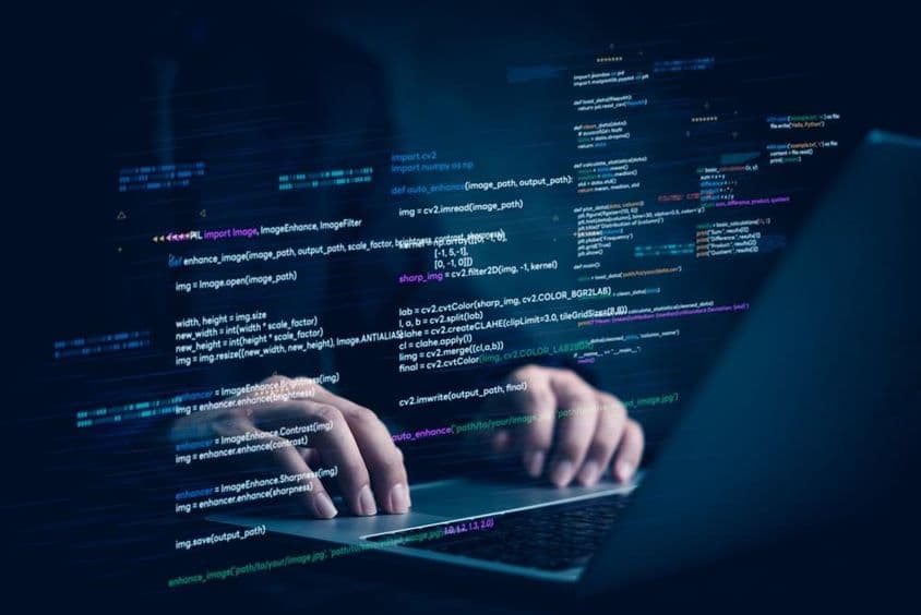 A notebook with two hands working, projecting a piece of computer code.