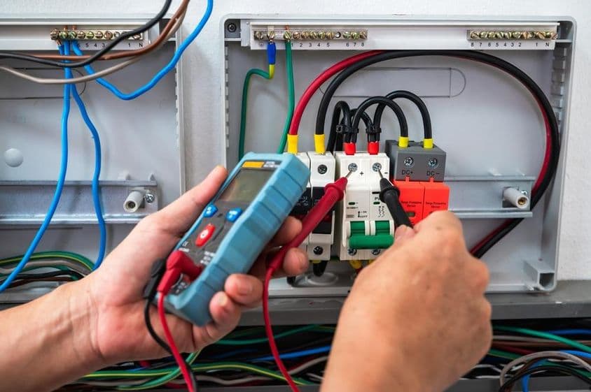 Electrician checking a power source with a meter.
