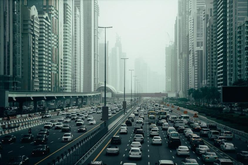 Dubai's crowded highway in the city, 2x7 lanes, skyscrapers on both sides.