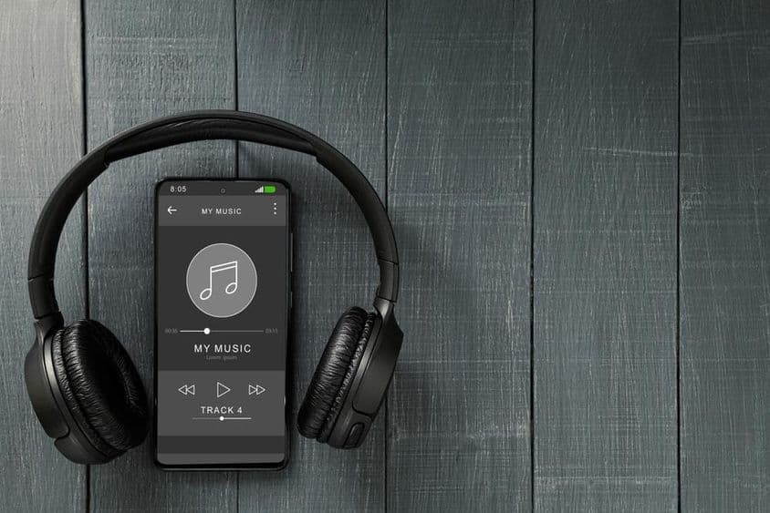 Music playback running on a phone, with headphones next to it.