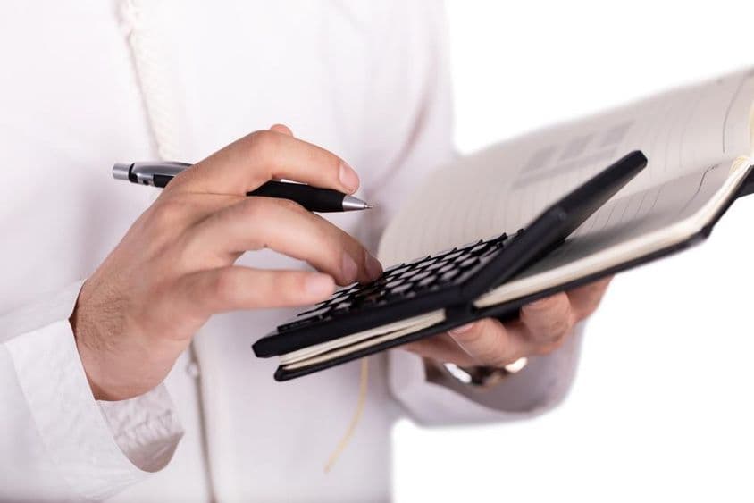 Calculator on notepad being operated by a hand.