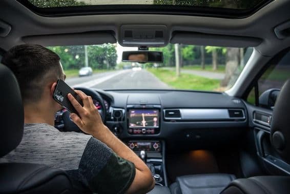 Young man using his phone while driving a car.