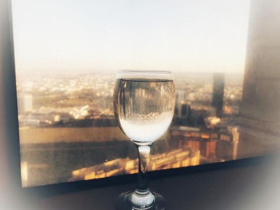 A glass of wine on the window with a city view.