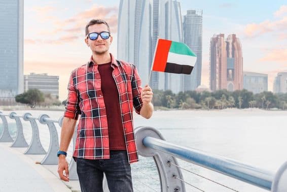 Young man in Dubai Marina holding a UAE flag.