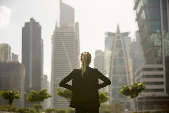 Woman standing with hands on hips looking at skyscrapers.