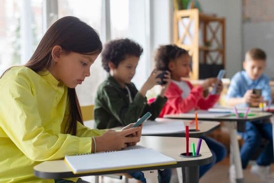 Children using phones in a classroom.