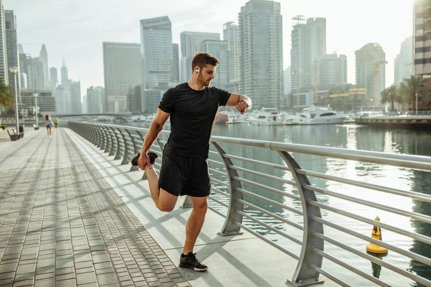 Young man stretching after a run by Dubai canal.