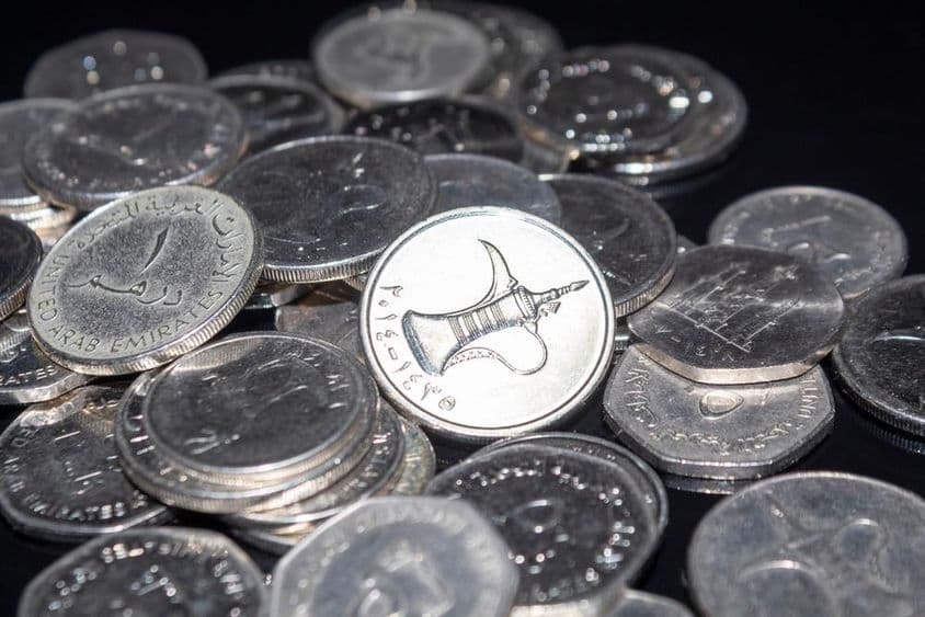 A handful of 1 dirham coins scattered around.