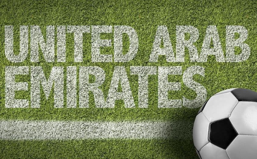 UAE inscription painted on grass with a soccer ball.