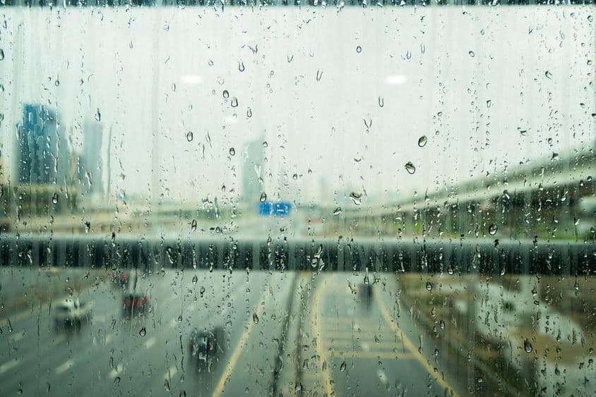 Raindrops on a window with a few blurred skyscrapers in the background.