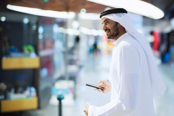 Arab man at Dubai airport holding a phone.