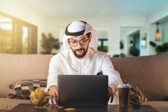 Arab man studying with a laptop.