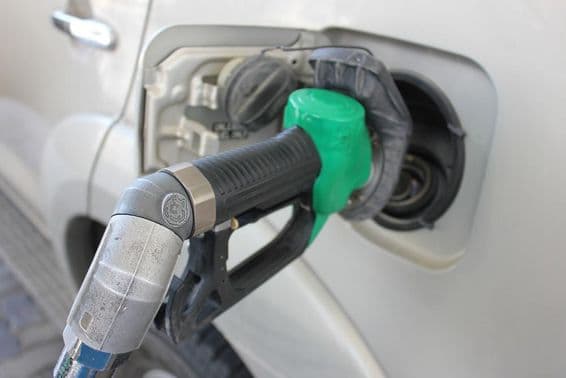 Refueling at a gas station into a white car.