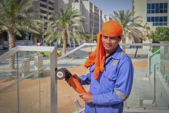 Dubai worker polishing railing.