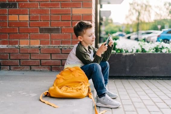 Boy using a phone on school steps.