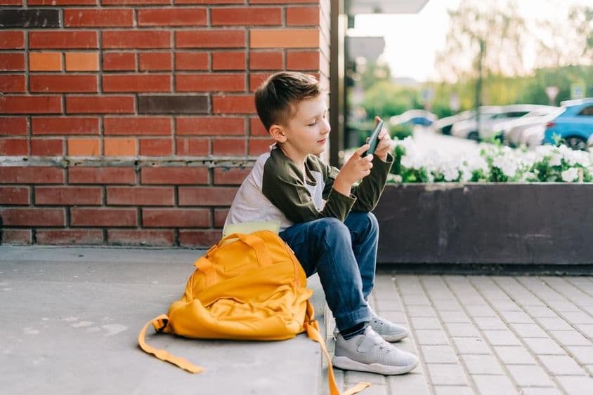 Boy using a phone on school steps.