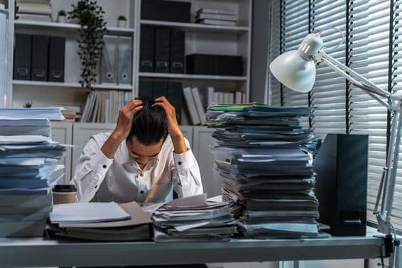 Office worker holding head due to overwhelming work.
