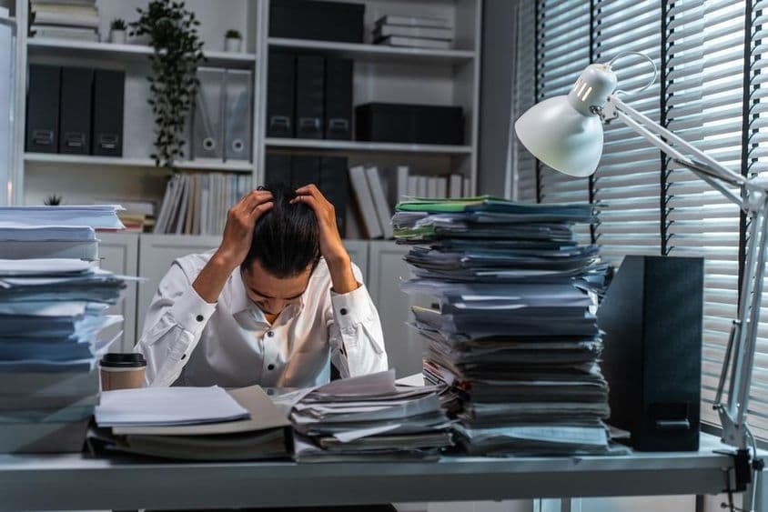 Office worker holding head due to overwhelming work.